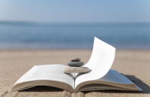 livre ouvert et galets posés dessus sur une plage - hotel la baule escoublac