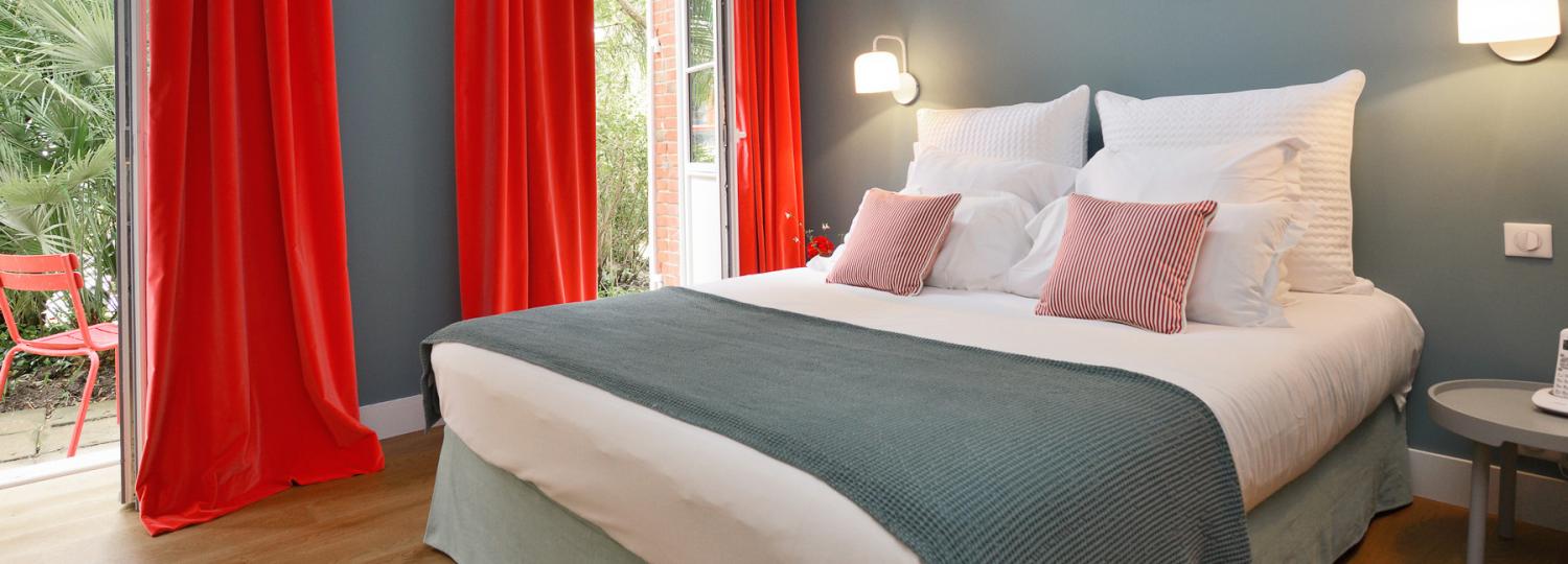 chambre moderne avec lit double et rideaux rouges - hotel la baule